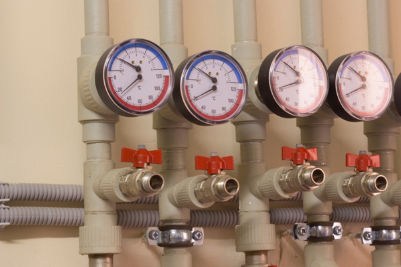 Commercial Water Heater Maintenance. A number of identical manometers stand on plastic pipes with red valves.